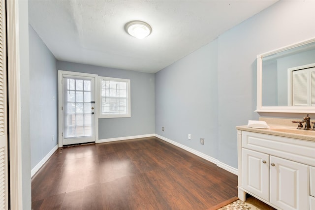 interior space with dark wood-style floors, baseboards, and a sink