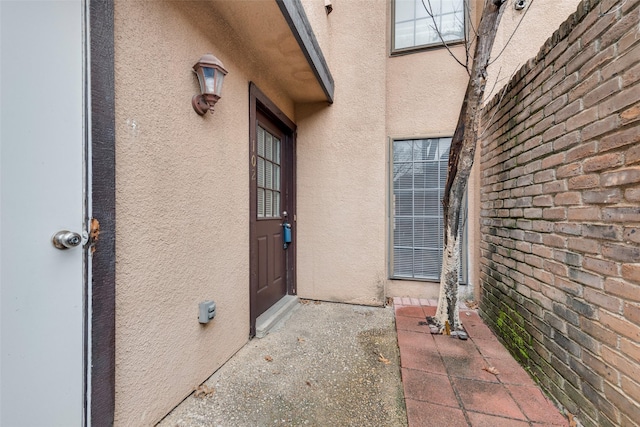 entrance to property with fence and stucco siding