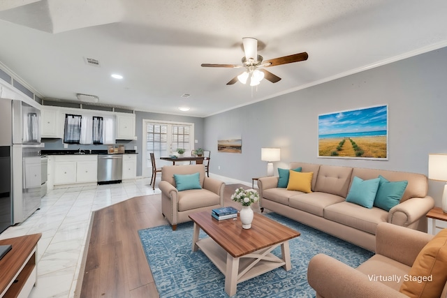 living room with ornamental molding, visible vents, baseboards, and a ceiling fan