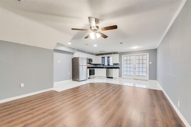 unfurnished living room featuring ceiling fan, light wood finished floors, a textured ceiling, and baseboards