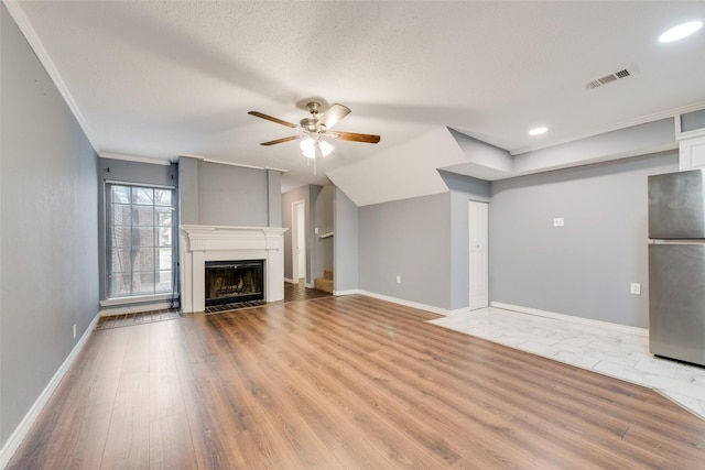 unfurnished living room with visible vents, a ceiling fan, a textured ceiling, light wood-type flooring, and baseboards