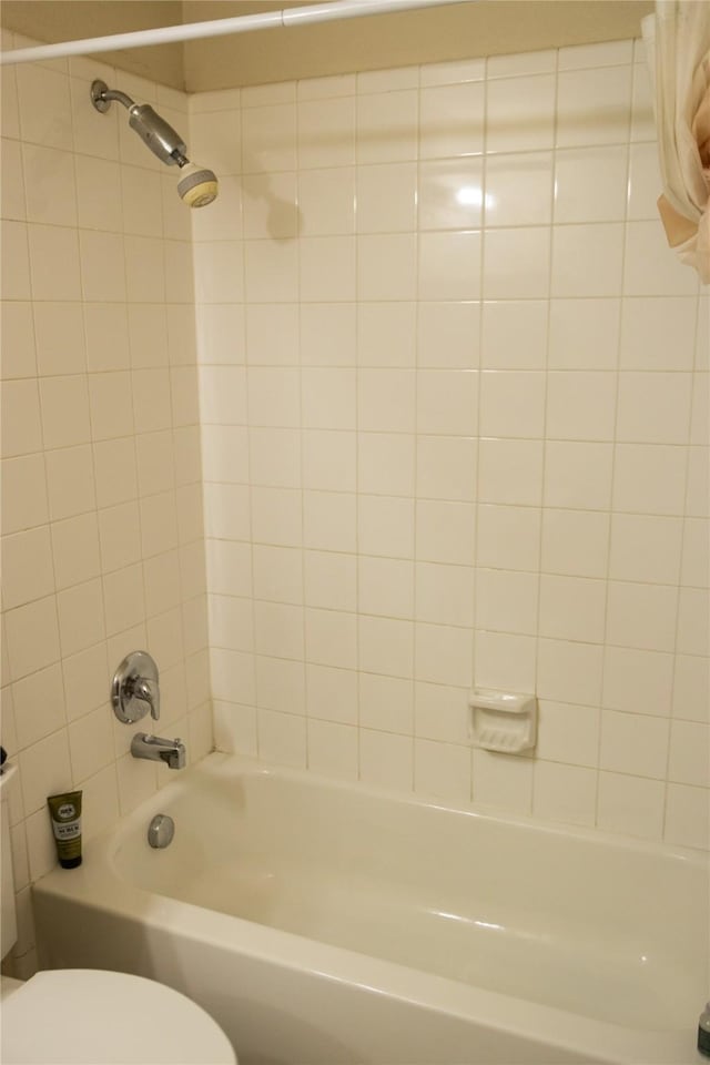 bathroom featuring tiled shower / bath combo and toilet