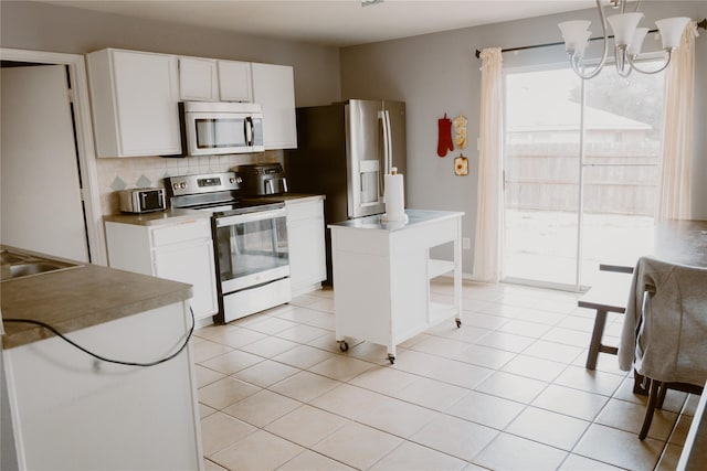 kitchen featuring decorative backsplash, white cabinets, light tile patterned floors, and appliances with stainless steel finishes