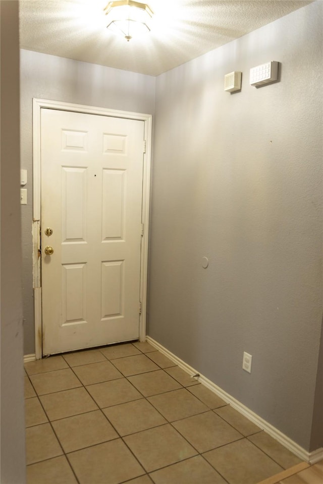 doorway featuring light tile patterned floors and a textured ceiling