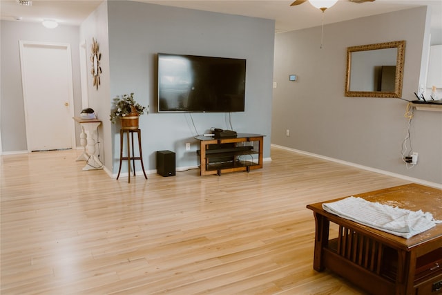 living area featuring visible vents, baseboards, ceiling fan, and wood finished floors