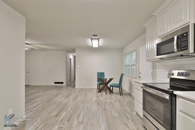 kitchen featuring tasteful backsplash, white cabinetry, appliances with stainless steel finishes, and light wood-type flooring