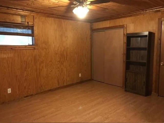 interior space with ceiling fan, wooden ceiling, light hardwood / wood-style floors, and wood walls