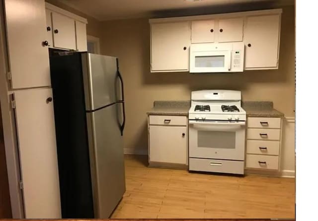 kitchen with white cabinetry, light wood-type flooring, and white appliances