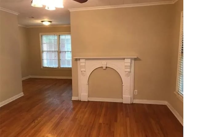 unfurnished living room with dark wood-type flooring, ornamental molding, and ceiling fan