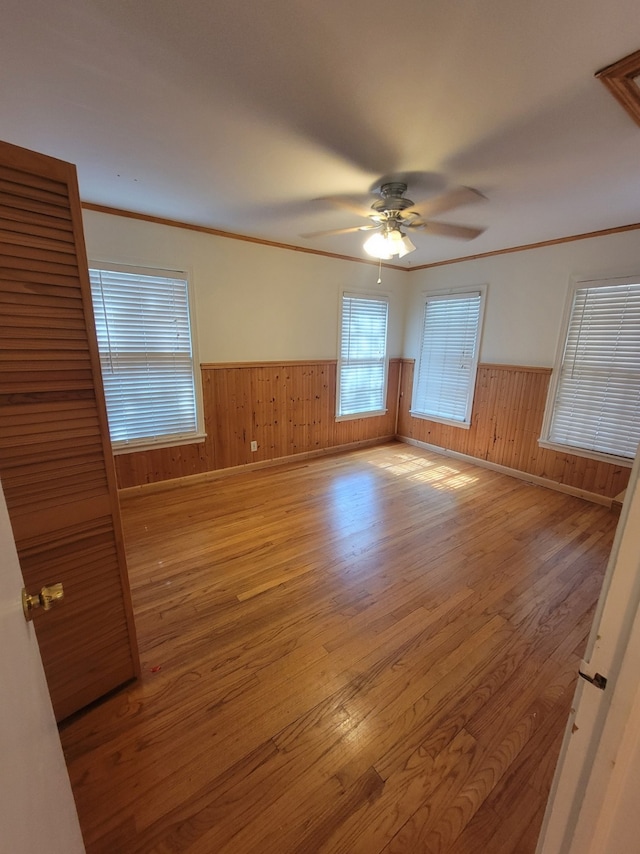 spare room featuring ceiling fan, ornamental molding, and light wood-type flooring