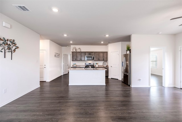 kitchen with dark wood-type flooring, dark brown cabinetry, stainless steel appliances, and an island with sink