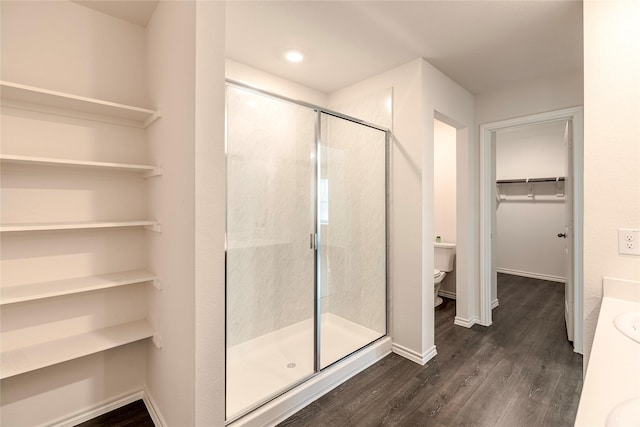 bathroom with hardwood / wood-style flooring, vanity, toilet, and a shower with door