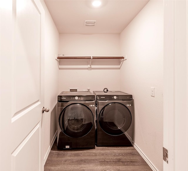 clothes washing area featuring wood-type flooring and independent washer and dryer