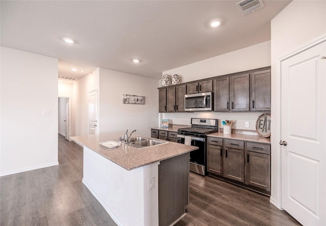 kitchen featuring sink, appliances with stainless steel finishes, dark brown cabinets, dark hardwood / wood-style floors, and an island with sink