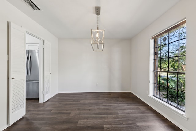 unfurnished dining area with dark wood-type flooring and a chandelier