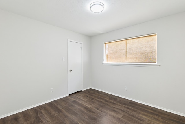 unfurnished room with dark wood-type flooring