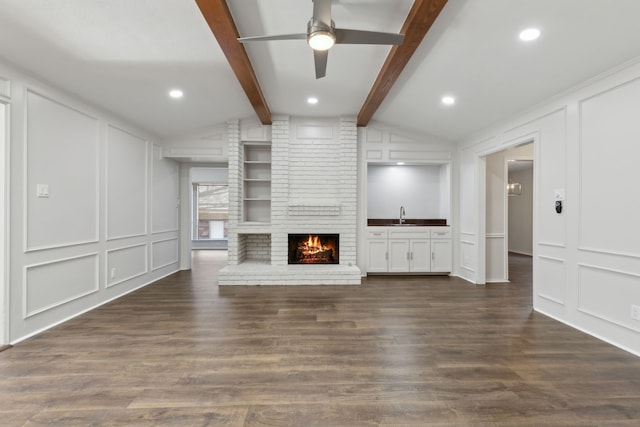 unfurnished living room featuring ceiling fan, a fireplace, dark hardwood / wood-style floors, and vaulted ceiling with beams