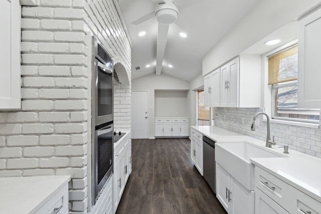 kitchen with appliances with stainless steel finishes, white cabinetry, vaulted ceiling with beams, backsplash, and dark wood-type flooring