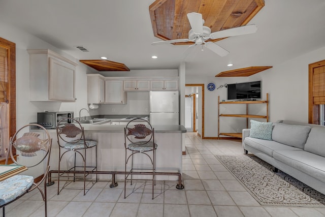 kitchen with sink, a kitchen breakfast bar, white cabinets, kitchen peninsula, and white fridge