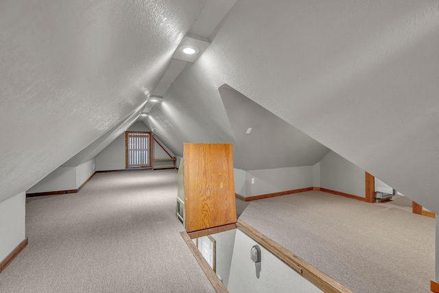 additional living space featuring lofted ceiling, light colored carpet, and a textured ceiling