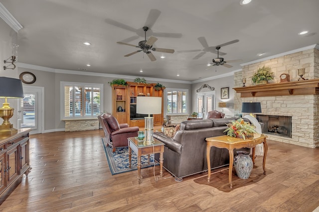 living room featuring crown molding, a fireplace, a healthy amount of sunlight, and light wood-type flooring