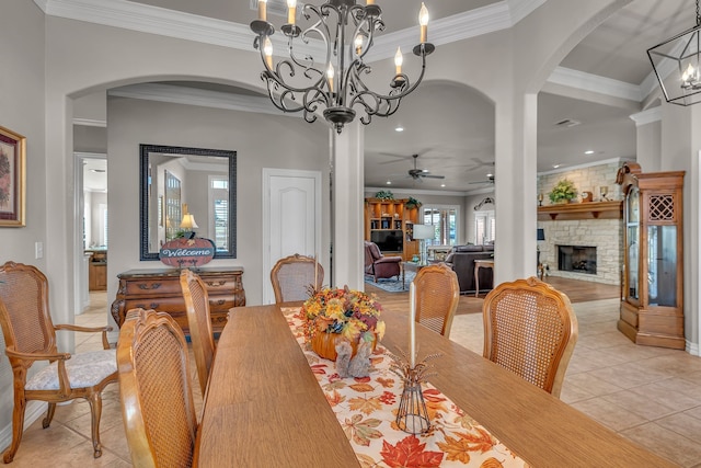 dining space featuring ceiling fan, ornamental molding, a fireplace, and light tile patterned floors