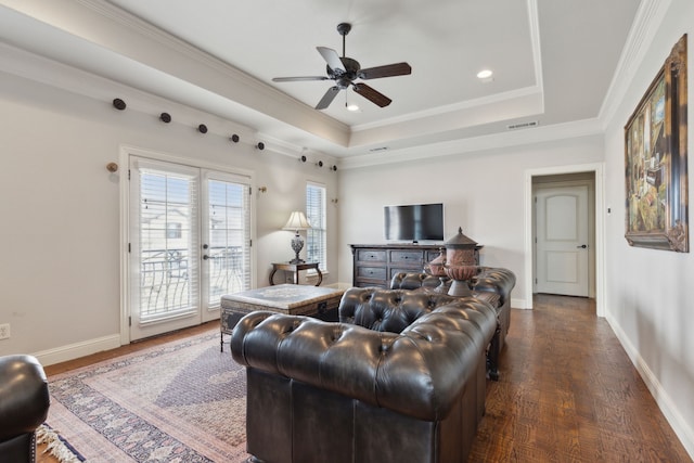 living room with a raised ceiling, crown molding, dark hardwood / wood-style floors, and ceiling fan