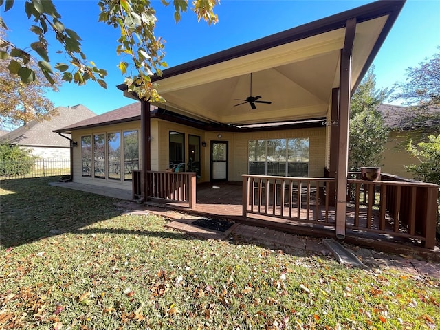 rear view of house featuring a wooden deck, ceiling fan, and a yard