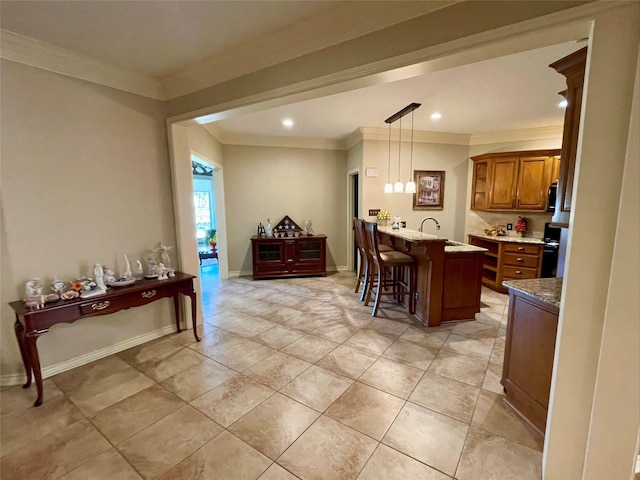 kitchen with hanging light fixtures, a breakfast bar area, ornamental molding, and sink