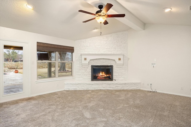 unfurnished living room featuring ceiling fan, a stone fireplace, lofted ceiling with beams, and carpet