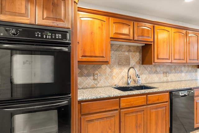 kitchen featuring sink, decorative backsplash, light stone counters, and black appliances