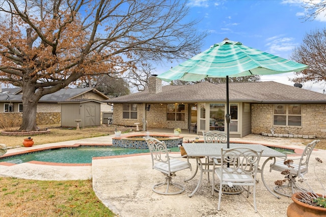 view of pool with an in ground hot tub, a patio, and a storage unit