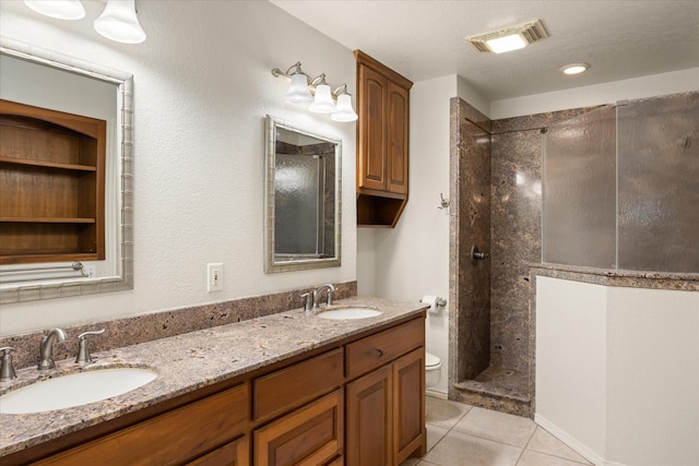 bathroom featuring tile patterned flooring, vanity, tiled shower, and toilet