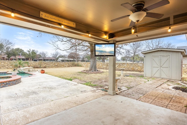 view of patio / terrace featuring an in ground hot tub, ceiling fan, and a shed