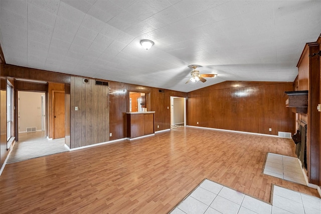 unfurnished living room with lofted ceiling, wood walls, ceiling fan, and light hardwood / wood-style flooring