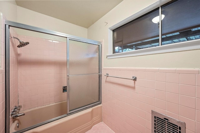 bathroom featuring bath / shower combo with glass door and tile walls