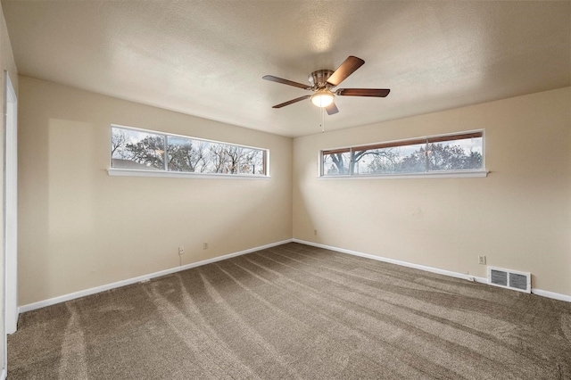 empty room featuring ceiling fan, a textured ceiling, a healthy amount of sunlight, and carpet flooring