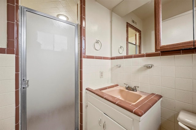 bathroom featuring tile walls, vanity, a shower with door, and toilet