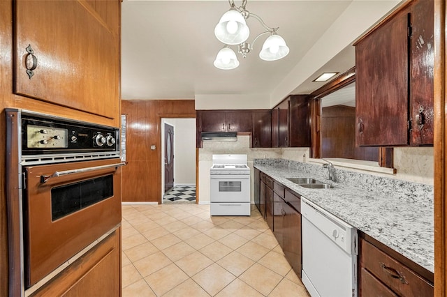 kitchen featuring wooden walls, sink, hanging light fixtures, white appliances, and an inviting chandelier