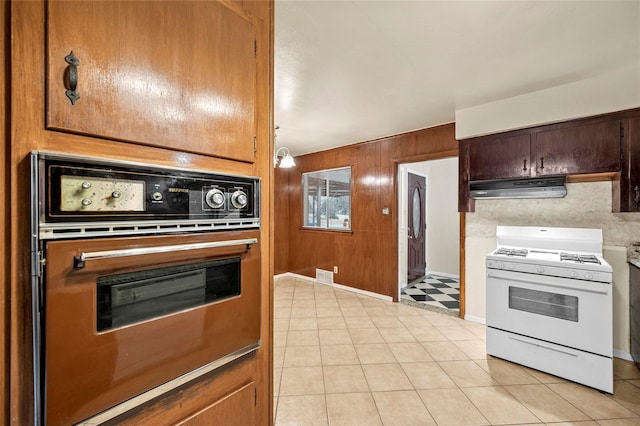 kitchen with extractor fan, gas range gas stove, hanging light fixtures, wooden walls, and wall oven