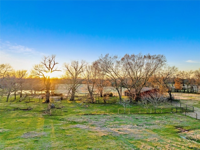 yard at dusk with fence and a rural view