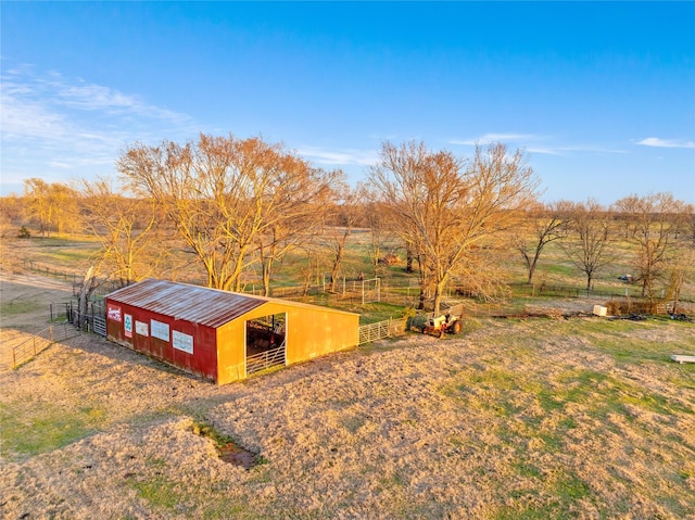 view of pole building with an exterior structure, a rural view, and fence