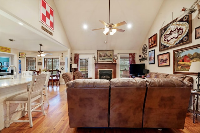 living room with a healthy amount of sunlight, sink, a brick fireplace, and light wood-type flooring