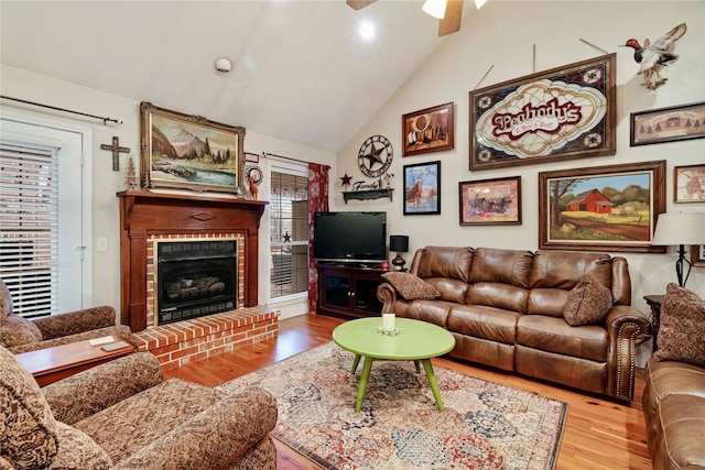 living room featuring a brick fireplace, hardwood / wood-style flooring, high vaulted ceiling, and ceiling fan