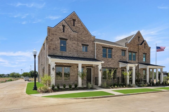 view of property featuring metal roof, brick siding, a standing seam roof, and fence