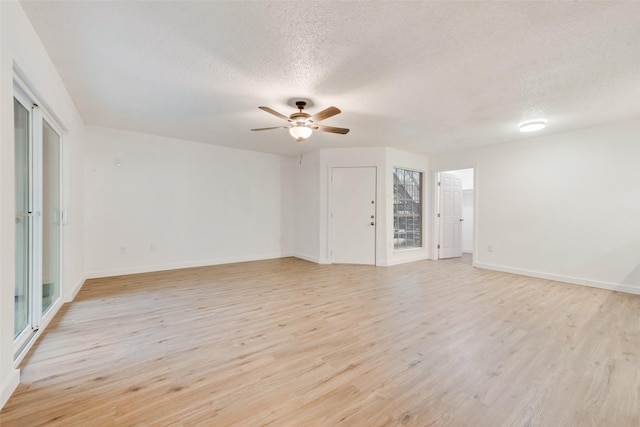 empty room with ceiling fan, light hardwood / wood-style floors, and a textured ceiling