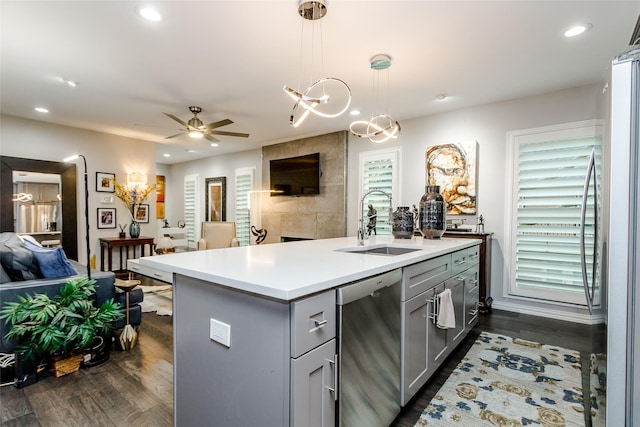 kitchen featuring sink, hanging light fixtures, gray cabinets, an island with sink, and stainless steel appliances