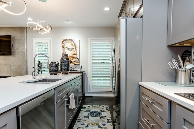 kitchen featuring pendant lighting, stainless steel refrigerator, dishwasher, sink, and gray cabinetry