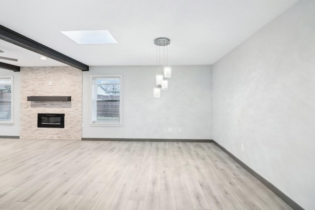 unfurnished living room featuring a fireplace, light hardwood / wood-style flooring, and beamed ceiling