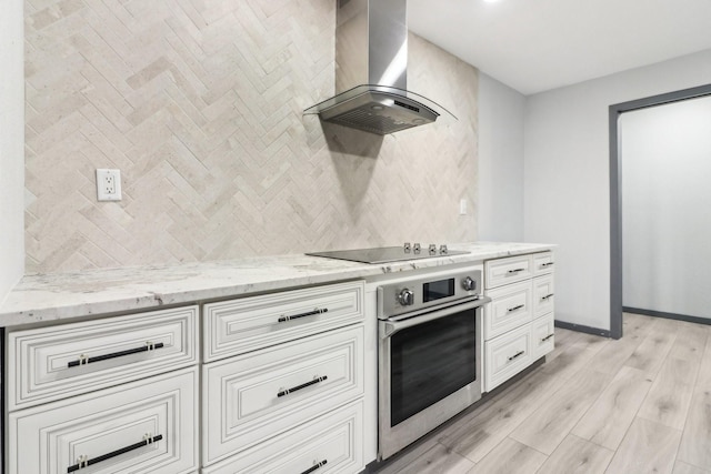 kitchen with oven, backsplash, island exhaust hood, light stone countertops, and black electric cooktop